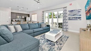 A modern living room with a grey sectional sofa, a white coffee table, and a large window with curtains. - Spacious 3-bedroom apartment with AC, WiFi in amazing Kissimmee (Kissimmee)
