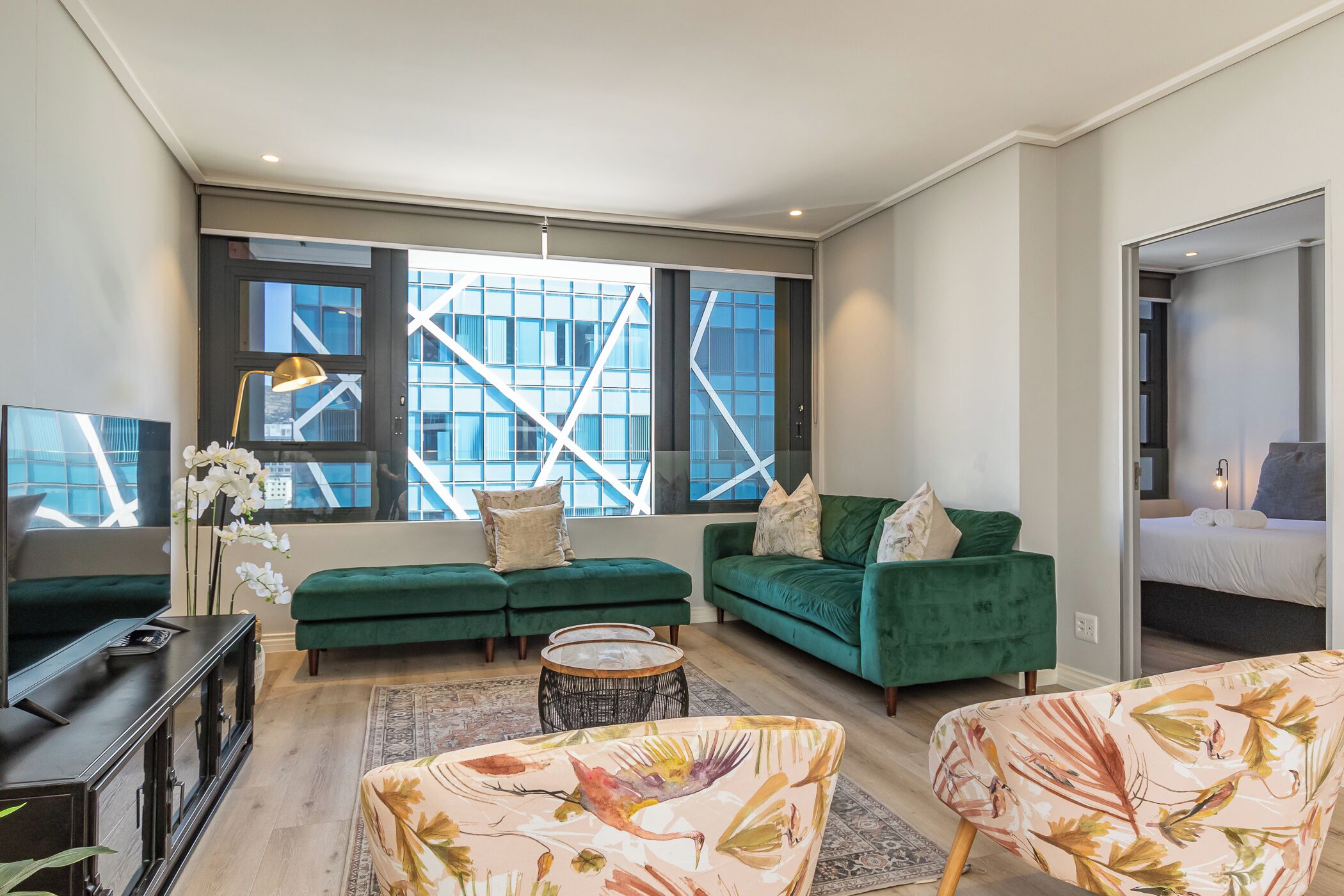 A modern living room with a green sofa, a round coffee table, and a television.