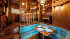Un intérieur en bois comprenant un coin repas avec un banc rembourré bleu et une table en bois, le tout disposé pour accueillir quatre personnes.