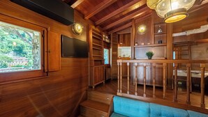 Un intérieur en bois avec un escalier, un canapé bleu et un coin repas agrémenté d’une rambarde.