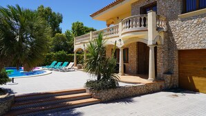 A poolside area with a stone building, a pool, and lounge chairs. - Spacious villa with private pool near the beach in Costa Brava (Sant Pere Pescador)