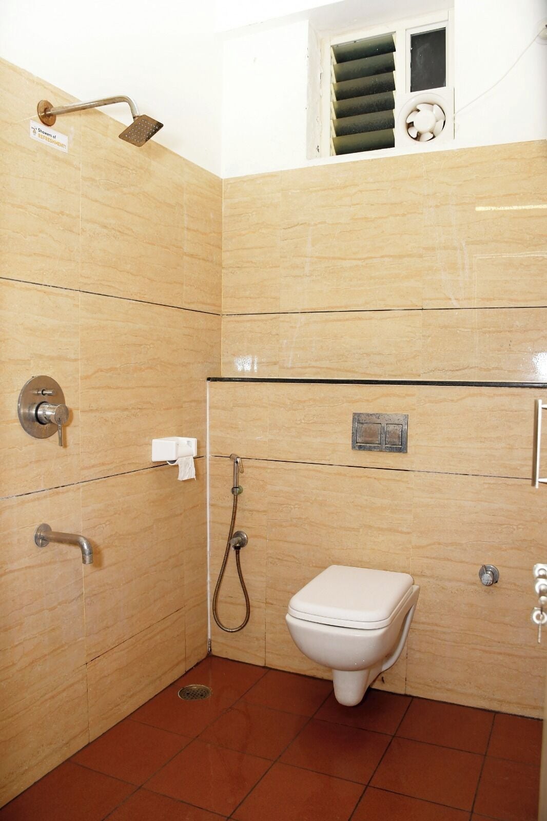 A bathroom with a shower, toilet, and a towel dispenser.