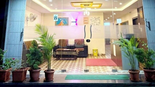 The entrance of a hotel named 'ARSHA COMFORTS' with a reception area, seating, and potted plants. - HARSHA COMFORTS (Chikkamagaluru)