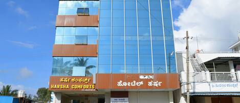 Un edificio de varios pisos con un letrero que dice 'Harsha Comforts' en la planta baja.