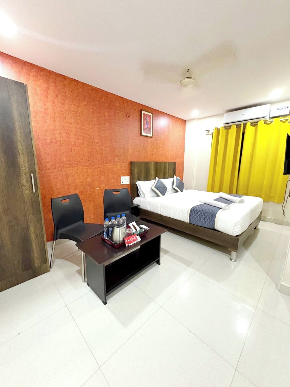 A hotel room with a bed, a desk with a chair, a coffee table, and a wall-mounted air conditioner.