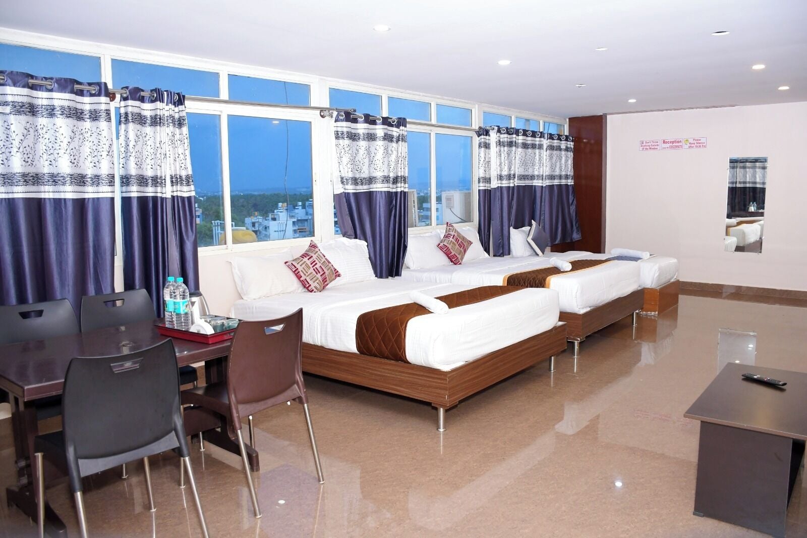 Habitación de hotel con una cama grande, dos mesitas de noche, un escritorio y sillas.