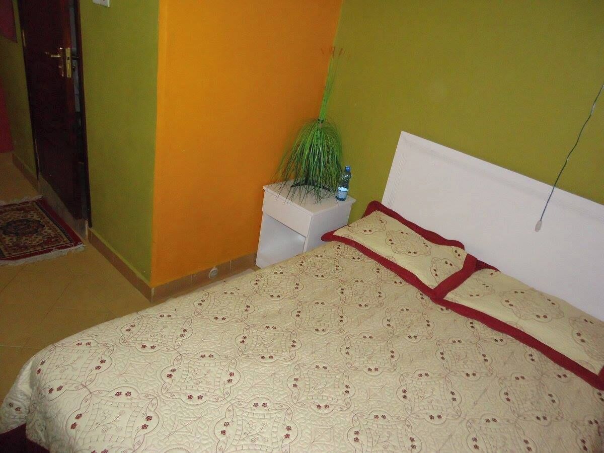 A bedroom with a bed, a nightstand, and a green wall.