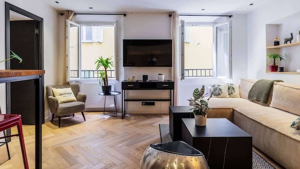 En moderne stue med sofa, sofabord, fjernsyn og et lille sofabord med en plante.