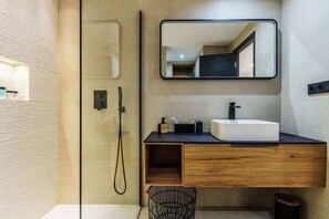 Ein modernes Badezimmer mit Duschkabine aus Glas, einem Holzwaschtisch mit weißem Waschbecken und einem großen Spiegel.