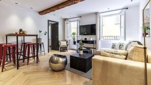 En moderne stue med sofa, røde skamler, et sofabord og et fjernsyn.