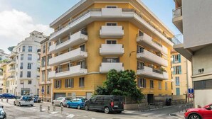 A multi-story residential building with balconies, a parking area, and a street view. - Studio apartment in the Port of Nice (Niza)