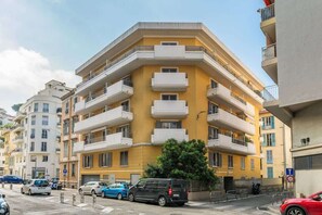 A multi-story residential building with balconies, a parking area, and a street view. - Studio apartment in the Port of Nice (Niza)