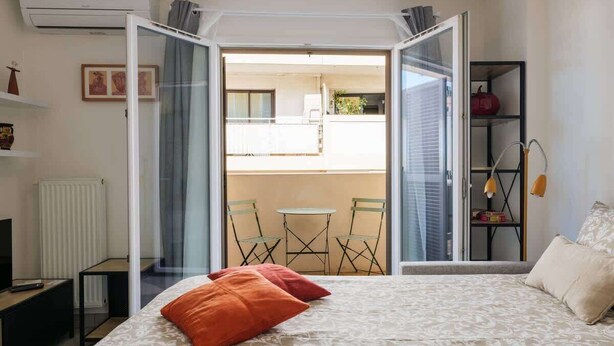 A bedroom with a bed, a TV, a radiator, a wardrobe, and a balcony with chairs and a table. - Studio apartment in the Port of Nice (Niza)