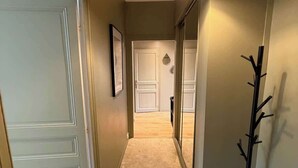 A hallway with a light fixture, a coat rack, and a door leading to another room. - Charming 2-bedroom apartment on Avenue Jean Médecin (Niza)