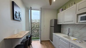 A modern kitchen with a wooden dining table, chairs, a refrigerator, a microwave, and cabinets. - Charming 2-bedroom apartment on Avenue Jean Médecin (Niza)