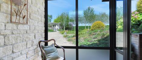A room with a large window, a wicker chair with a cushion, and a metal rack.
