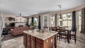 A spacious kitchen with a central island, dining area with chairs, and a sofa.