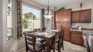 A kitchen with wooden cabinets, a dining table with chairs, and a hanging light fixture.