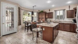 A kitchen with a central island, wooden cabinets, and a dining area with chairs.