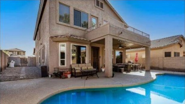 A two-story house with a swimming pool, outdoor seating, and a covered patio area.