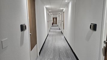 Un pasillo de hotel con una distribución larga y estrecha, con puertas que tienen teclados numéricos y un pasillo central.