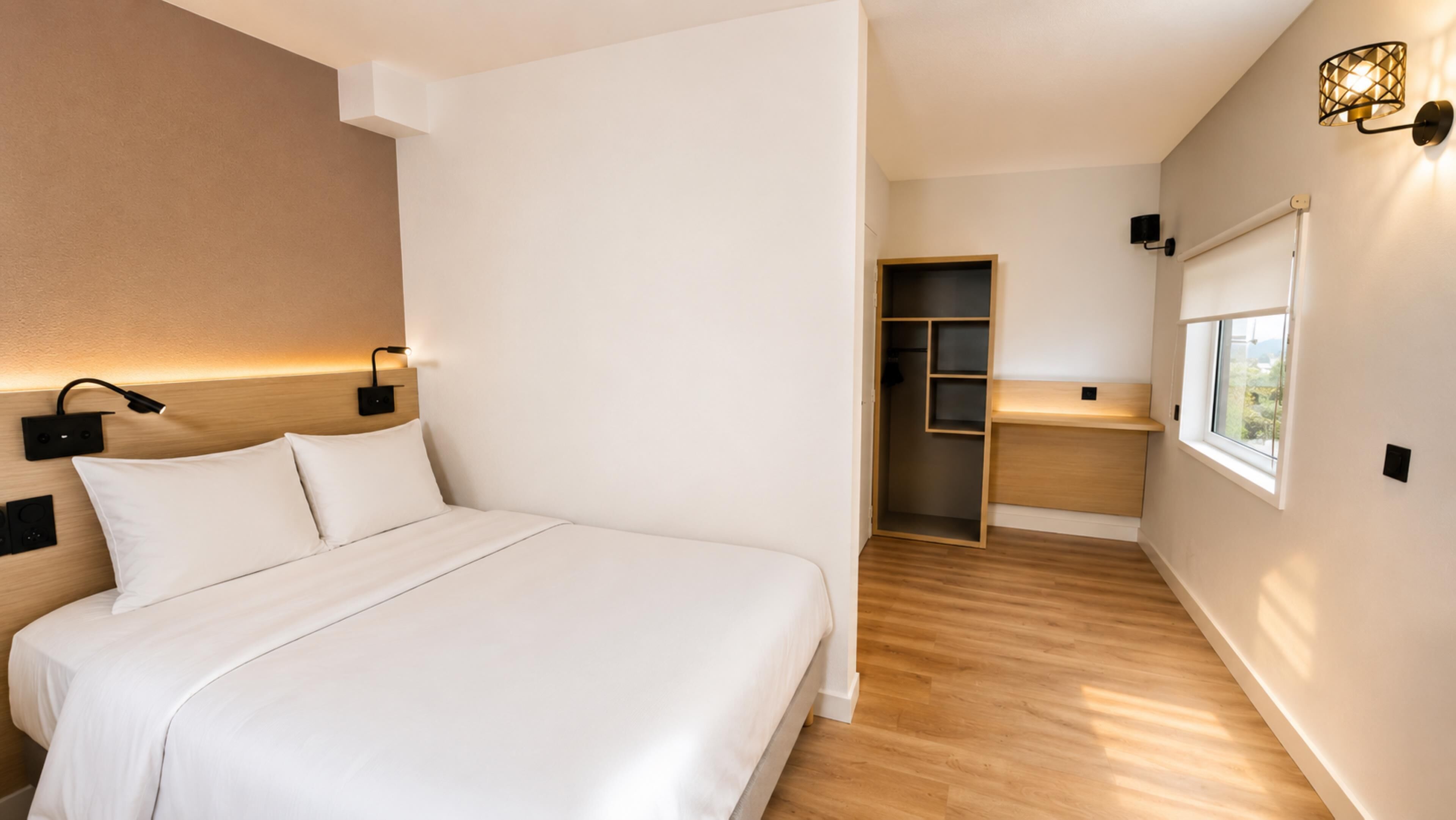 A modern bedroom with a bed, bedside lamps, a walk-in closet, and a window.
