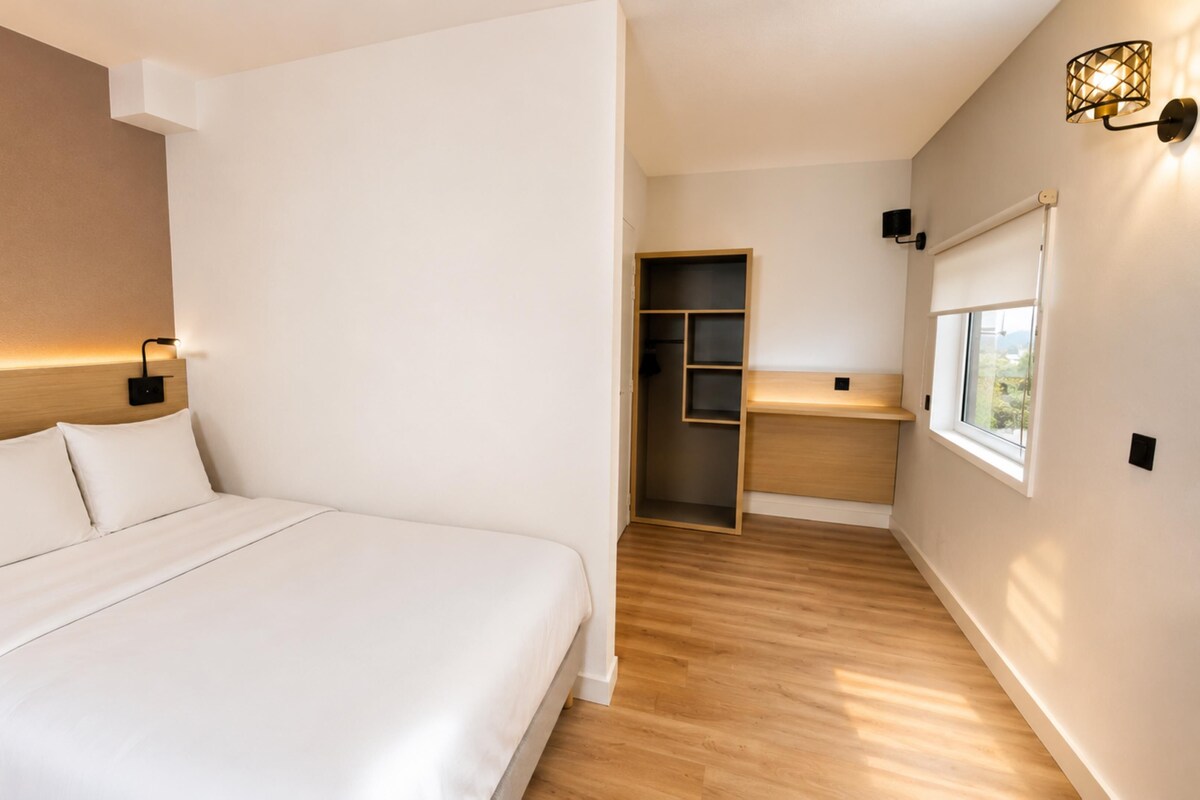 Un dormitorio moderno con cama, lámparas de noche, armario vestidor y ventana.