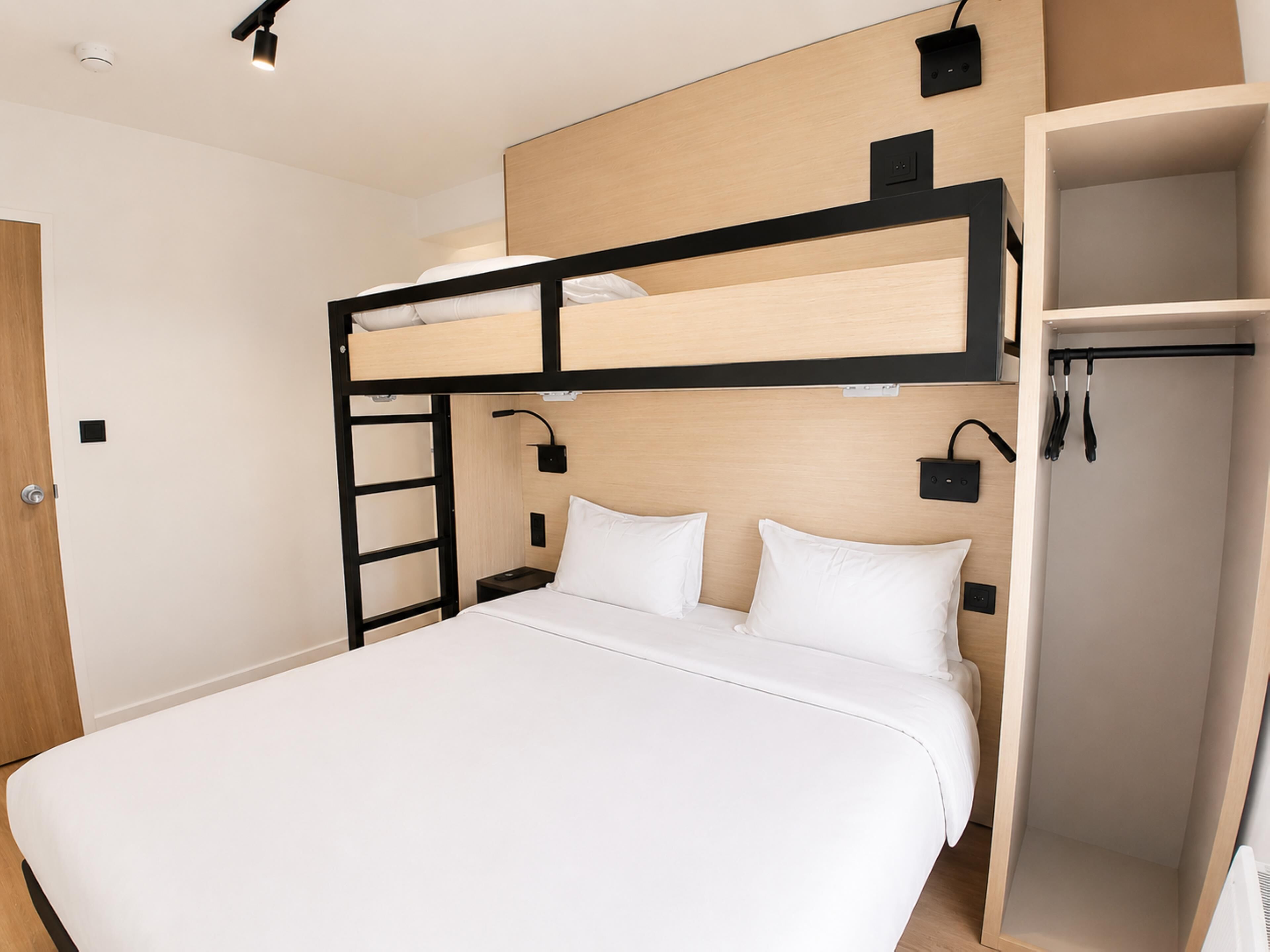 A bunk bed room with a wooden headboard, a bedside table, and a wardrobe.
