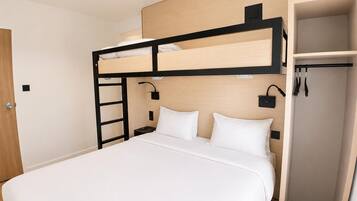 Une chambre avec un lit superposé, une tête de lit en bois, une table de chevet et une armoire.