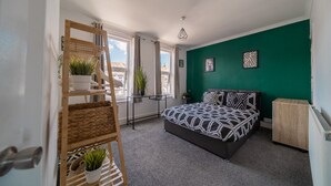 A bedroom with a bed, a green wall, a window, and a plant. - Castle View Haven-Quirky and Cosy 5 Bedroom in Strood/Rochester with Castle view (Rochester)