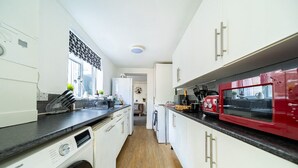 A modern kitchen with white cabinets, a red microwave, and a washing machine. - Castle View Haven-Quirky and Cosy 5 Bedroom in Strood/Rochester with Castle view (Rochester)