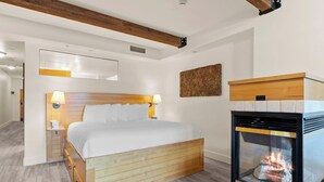 Ein Schlafzimmer mit Bett, Nachttischlampen, einem Holz-Kopfteil, einem Kamin und einem an der Wand hängenden Kunstwerk.