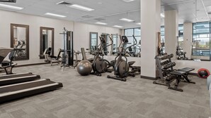Ein geräumiges Fitnessstudio mit verschiedenen Trainingsgeräten, großen Fenstern und modernem, sauberem Design.