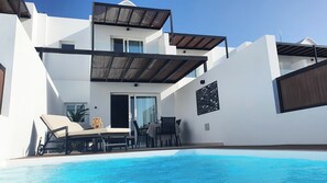 Ein modernes, zweistöckiges Gebäude mit Schwimmbad, Außenbereich zum Sitzen und einer überdachten Terrasse.