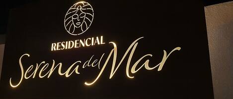 Une enseigne portant l’inscription « RESIDENCIAL Serena del Mar » et un logo stylisé au-dessus.