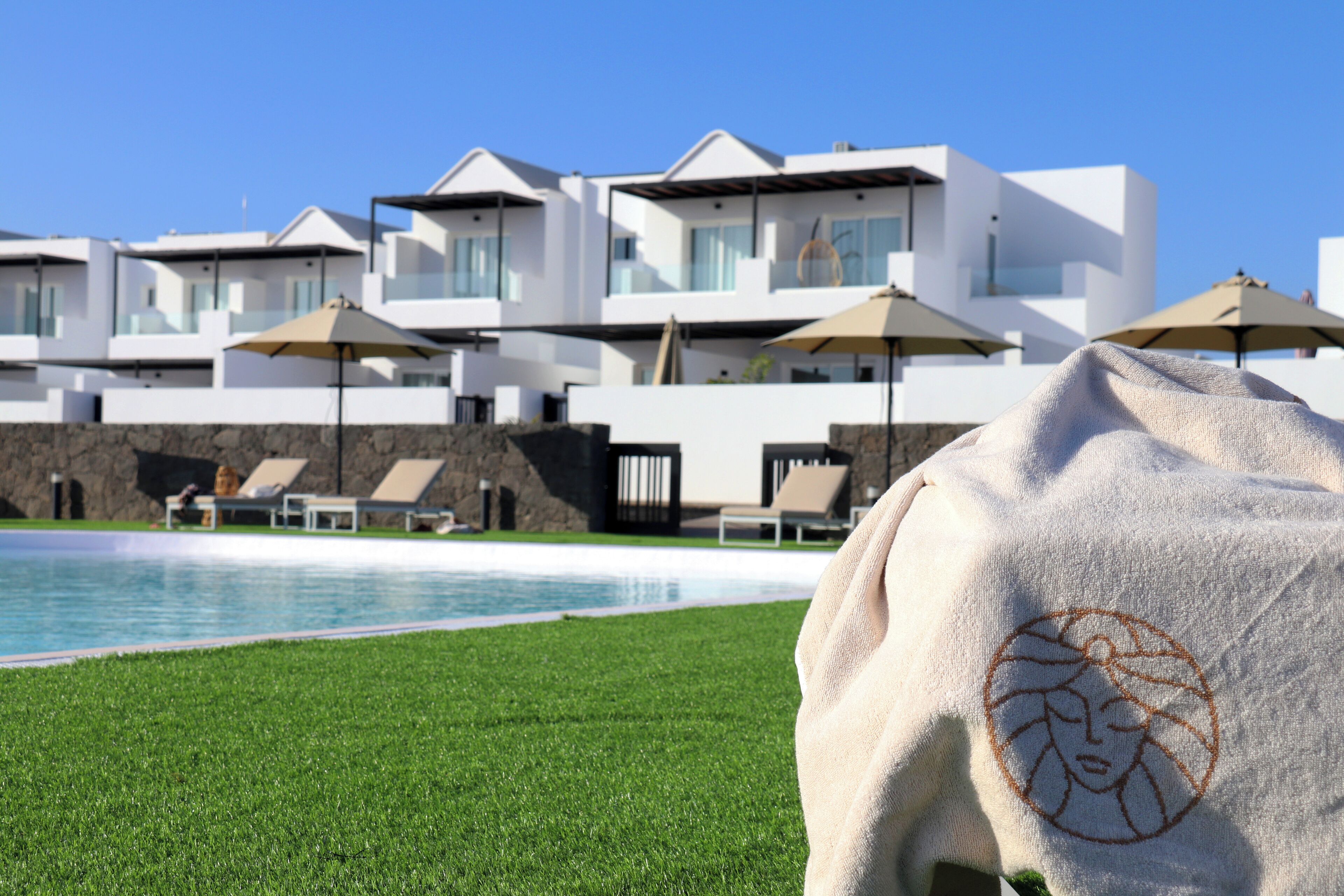 Ein modernes Hotel mit Pool, Liegestühlen und Sonnenschirmen.