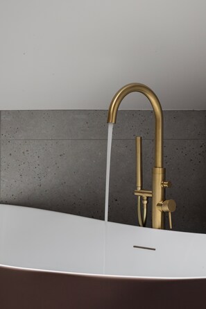Een badkamer met een moderne gouden kraan en een witte wastafel.