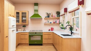 A kitchen with wooden cabinets, a green stove, a white refrigerator, and a window with a view.