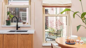 A kitchen with wooden cabinets, a sink, and a window with a view of a garden.