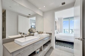 A modern bathroom with two sinks, a large mirror, and a view of a bedroom with a bed and a balcony. - This apartment is a 2 bedroom(s), 2 bathrooms, located in Hallandale, Miami, FL. (Hollywood)