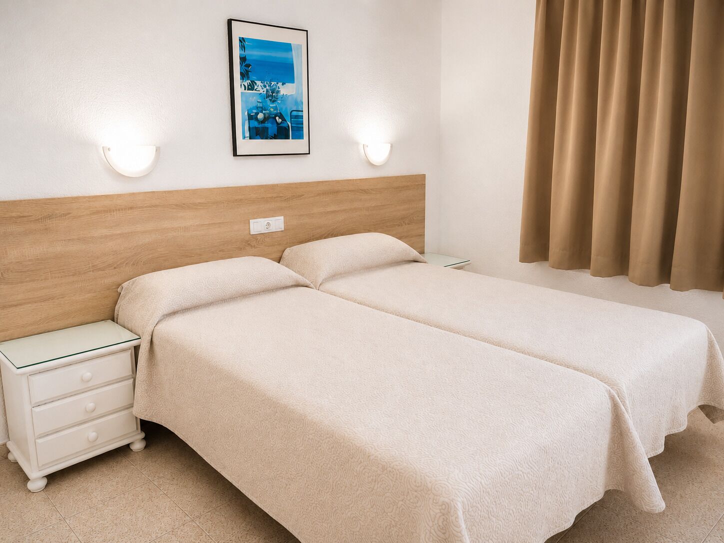 Un letto matrimoniale con testiera in legno, un comodino con cassetti, un quadro incorniciato appeso al muro e una finestra con tende.