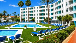 Ein Hotel mit Poolbereich, mehreren Balkonen und einer modernen Fassade.