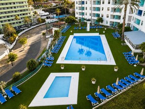 A hotel with a large rectangular pool, multiple lounge chairs, and a well-maintained lawn area. - APARTAMENTOS TAMARAGUA (San Bartolome de Tirajana)