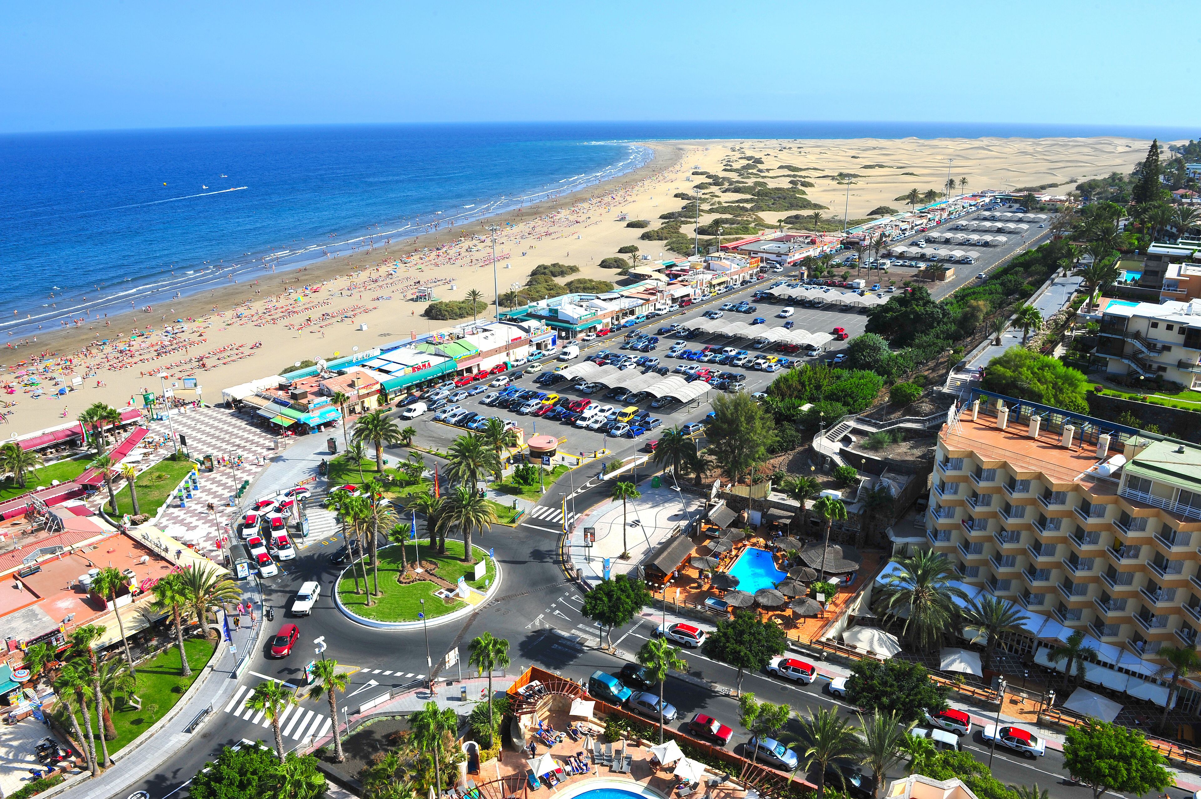 A coastal hotel with a beach view, parking facilities, and a central courtyard with palm trees.