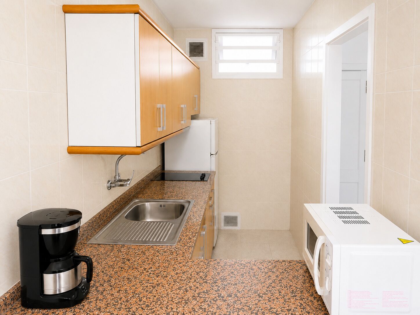 A compact kitchen with a coffee maker, a microwave, and a sink.
