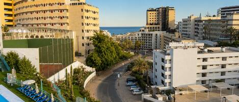 A hotel with multiple floors, a pool area, and a view of the sea.