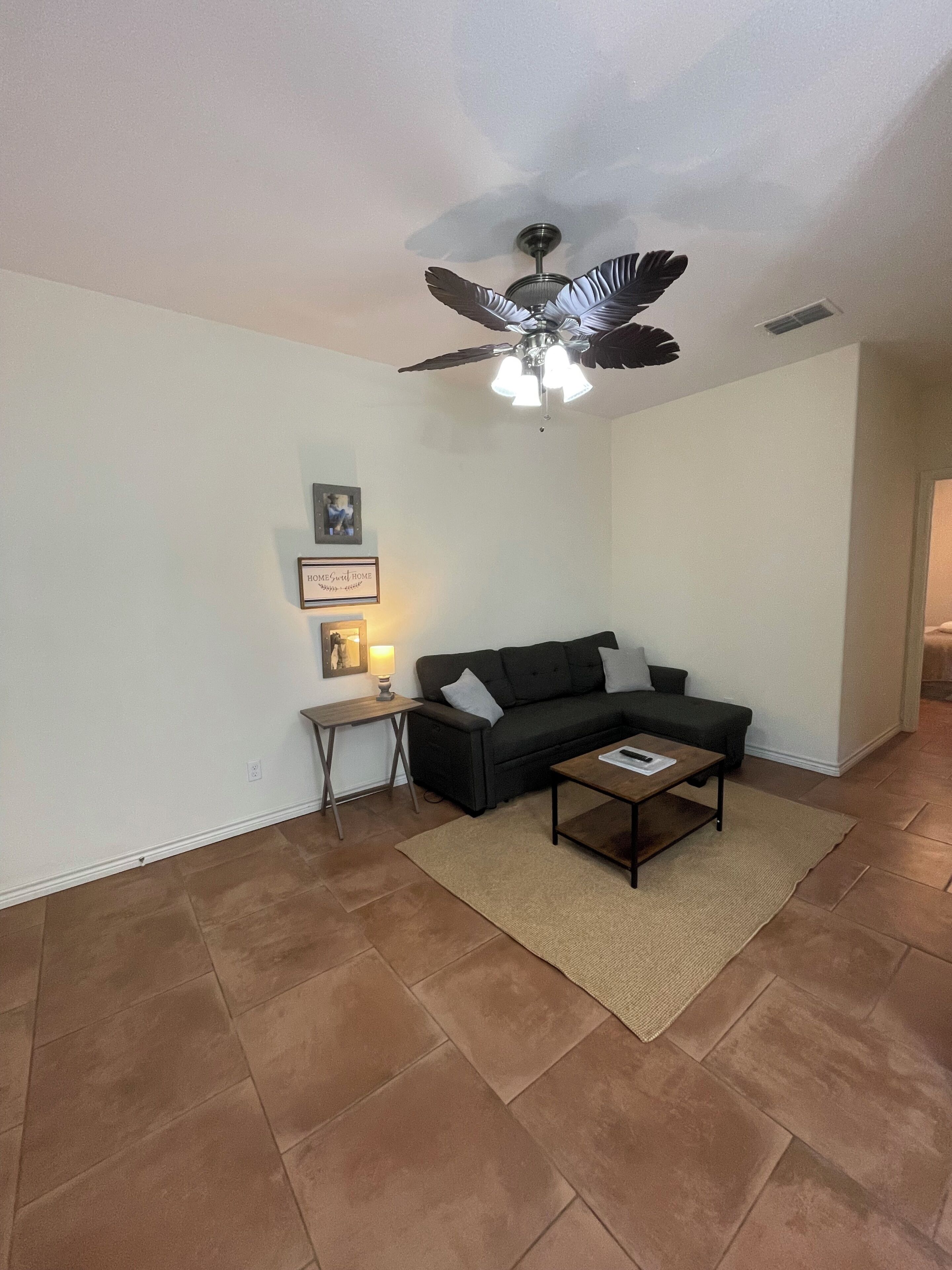 A living room with a ceiling fan, a sofa, a coffee table, and a rug.