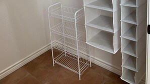 Un armario con estantes blancos y una cesta de alambre.