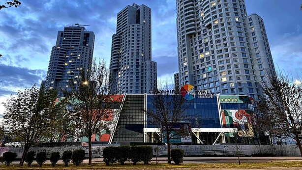 Un quartier urbain moderne, caractérisé par de grands immeubles, une vaste structure en verre et un drapeau.