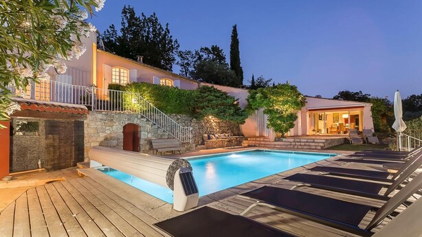 A private pool area with a wooden deck, lounge chairs, and a stone wall. - Country house with private pool, quiet comfort & nature (Seillans)